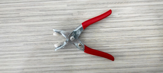 red and yellow pliers as a snap tool for making clothes buttons are made of stainless steel with...