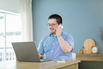 パソコンを見ながら電話をする大柄な日本人男性