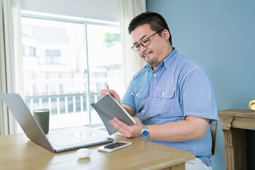 スケジュール帳に予定を書き込む大柄な日本人男性