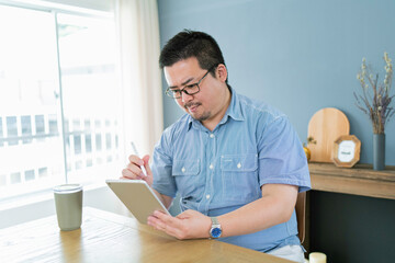 Fototapeta premium タブレット端末でイラストを描く大柄な日本人男性
