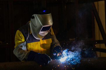 Handymen performing welding and grinding at their workplace in the workshop, while the sparks fly...