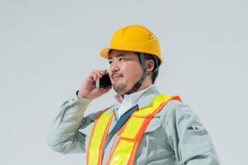 スマートフォンで電話をする作業服の男性