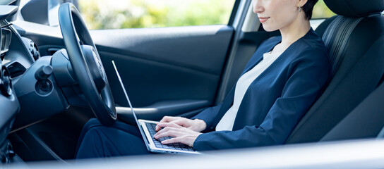 車内でパソコン作業をするスーツを着た女性