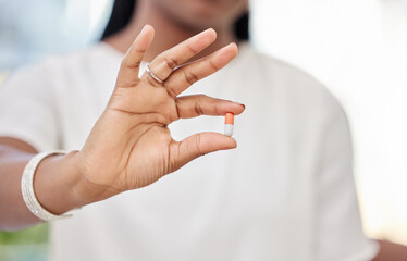 Medication, hand and woman with pill or antibiotic in house for healthcare, wellness and recovery. Female person, medical or medicine capsule in home for health, vitamin or supplement tablet