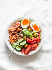 Tasty balanced lunch - grilled salmon, boiled egg, fresh vegetable salad on a light background, top view
