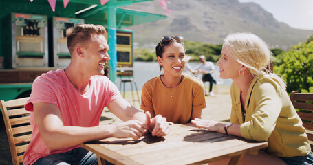 Funny, friends and talking at outdoor cafe table, communication and happy people bonding together. Group, smile or laughing at conversation in nature for comedy, joke or story in summer by food truck