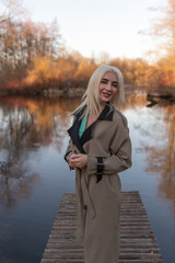 Portrait of a young beautiful blonde girl in a raincoat in the park.