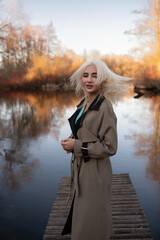 Portrait of a young beautiful blonde girl in a raincoat in the park.