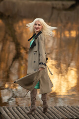 Portrait of a young beautiful blonde girl in a raincoat in the park.