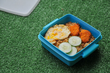 Lunch box containing fried rice, nuggets and eggs