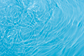 Blue water with ripples on the surface. Defocus blurred transparent blue colored clear calm water surface texture with splashes and bubbles. Water waves with shining pattern texture background.