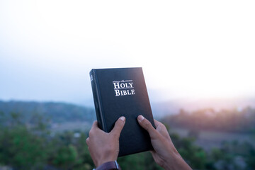 hands holding bible and lift up to the sky for pray for blessings to God.