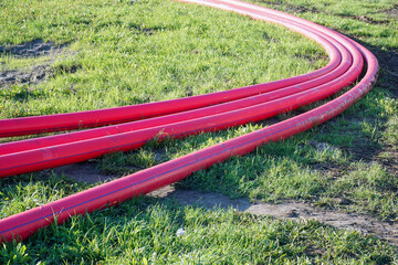 Four polyethylene pipes lie on the grass for laying a pipeline.