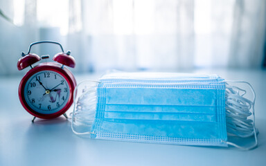 alarm clock and surgical mask on the table