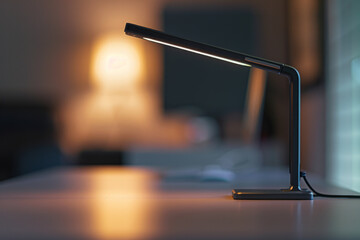 Fototapeta premium A single contemporary desk lamp with a minimalist silhouette and adjustable brightness, positioned on a clean desk, providing focused illumination for work or study. 