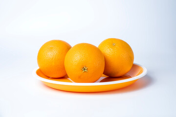 Fresh oranges on a plate isolated on a white background.