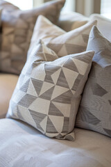 A set of modern geometric throw pillows with monochromatic patterns or subtle textures, arranged on a neutral-colored sofa, adding depth and sophistication to the decor. 
