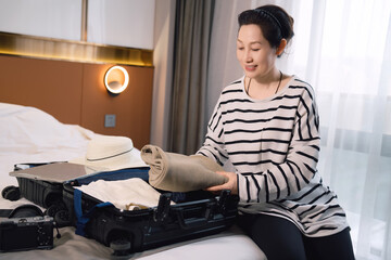 Woman Organizing Suitcase for Travel in Hotel Room