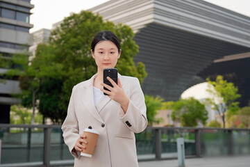 Professional Woman Using Smartphone Holding Coffee Cityscape
