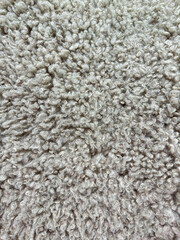 Detailed macro shot of dense, curly grey wool texture with natural fleece patterns for interior design and textiles.