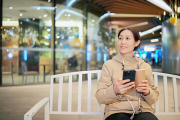 Woman Enjoying Coffee While Browsing on Smartphone at Mall