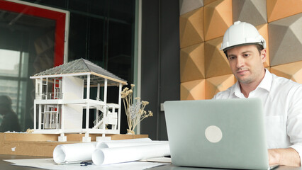 Portrait of professional male caucasian engineer using laptop analysis house construction with...