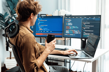 Working IT developer holding coffee cup with looking online software on pc at modern office on coding application screens, creating updated latest program firmware information version concept. Gusher.