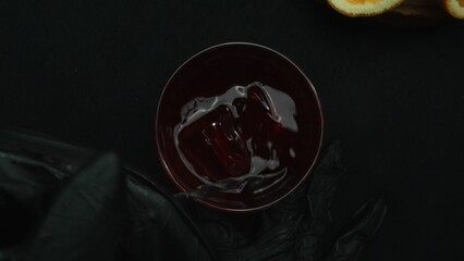 Top down view of bartender hand making and prepare Scarlet spritzer with black background. Close up...