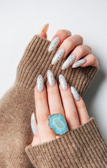 Hands with blue nail polish on cozy sweater