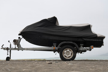 Wrapped motor boat scooter at marina under cover in summer season. Boat on stand on the shore, ...