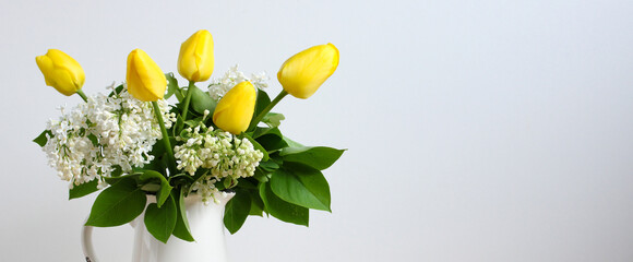 a floral banner with yellow tulips and lilac blossoms on a white background. copy space.
