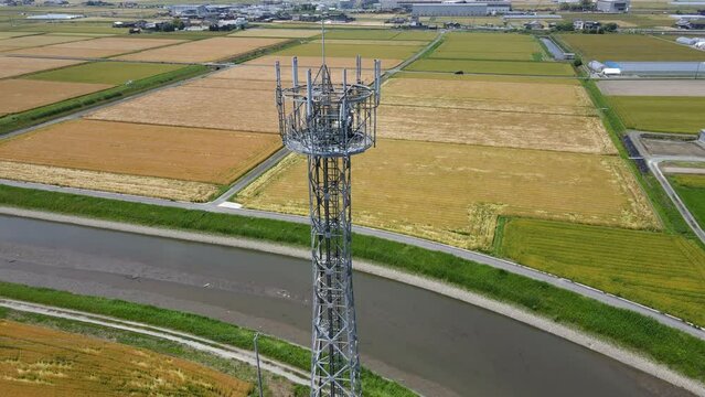 田園風景の中に立つ携帯電話基地局鉄塔　空撮でのパンダウン動画