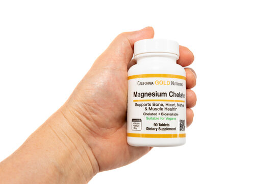 Fuji City, Shizuoka Prefecture, Japan - April 14, 2024: Hand holding Magnesium Chelate supplement 210 mg 90 Tablets (105 mg per Tablet) by California Gold Nutrition. Isolated on white background