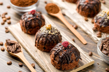 Round chocolate cakes. Decorated with candied raspberries. Wooden background