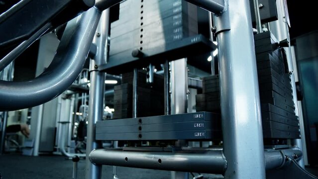 Weight stacked plates pull up and down. Weight machine at fitness gym. Black iron heavy plates. Sport equipment. Workout concept. Training in gym. Close-up in 4K, UHD