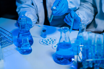 Medical or research scientist or doctor using looking at a test tube of clear solution in a lab or...