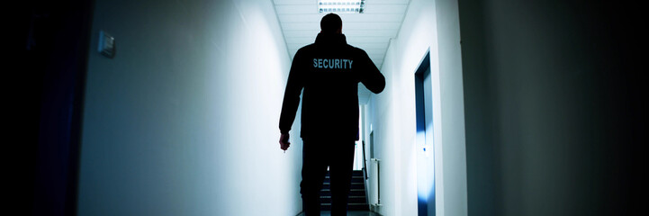 Male Security Guard Holding Flashlight Standing In Corridor