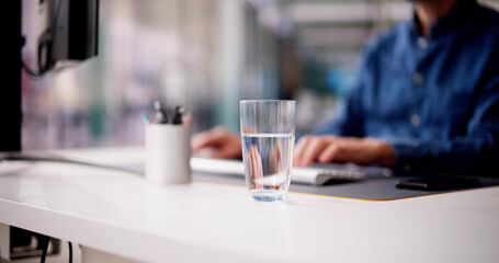 Glass Of Water On Desk And Man In Background