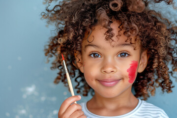 A young child with dark brown skin and curly hair is depicted holding an oil paintbrush in one hand while painting their cheek in the style of red lipstick using the other hand. The child wears overal