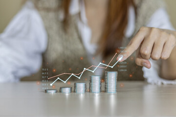 Hand pointing at a stack of coins and upward arrows on a graph indicating financial growth and...