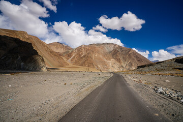 Spectacular high roads wind through rugged mountains beneath blue skies and the remote snow-capped...
