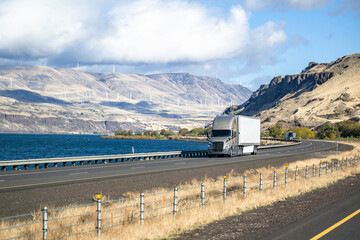Beige big rig long hauler semi truck transporting cargo in dry van semi trailer driving on the...