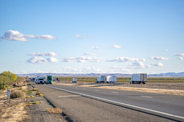 Convoy of the big rig semi trucks with semi trailers transporting cargo running in both directions