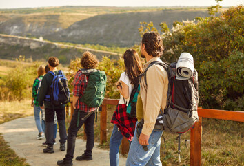 Group of men and women hikers with large backpacks looking into the distance during hiking in...