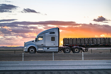 Profile of the gray big rig semi-truck with extended cab transporting boxes on the flat bed semi...