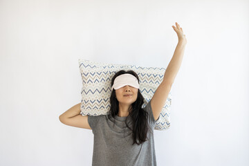Asian woman wake up with pillow and sleep mask on white background.