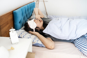 young Asian woman waking up in early morning lying on bed. Woman with eyes closed yawning in bed at home.