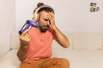 A man in a red shirt is holding a purple controller and looking at the camera