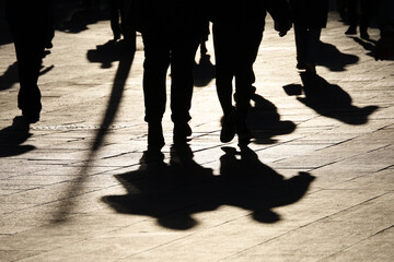 Black silhouettes and shadows of people on the street. Crowd walking down on sidewalk, concept of...