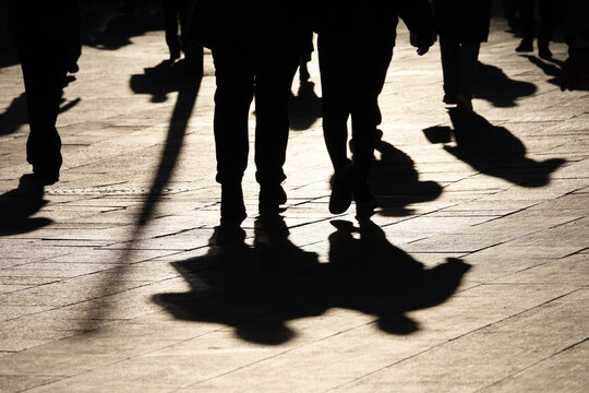 Black silhouettes and shadows of people on the street. Crowd walking down on sidewalk, concept of pedestrians, crime, society, city life